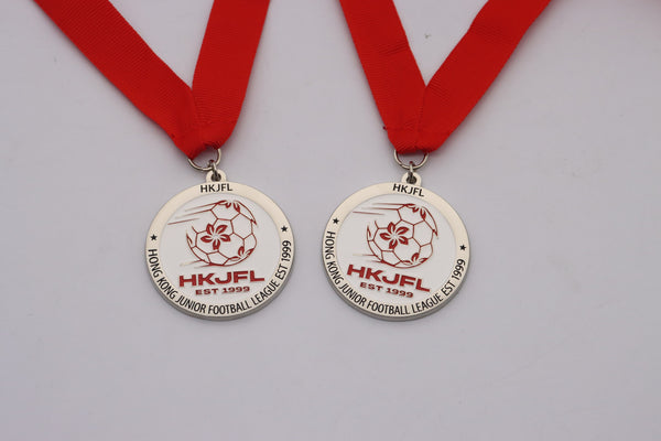 Two silver medals on red ribbons, each showing a red football and bauhinia design and the name of a Hong Kong junior football league.